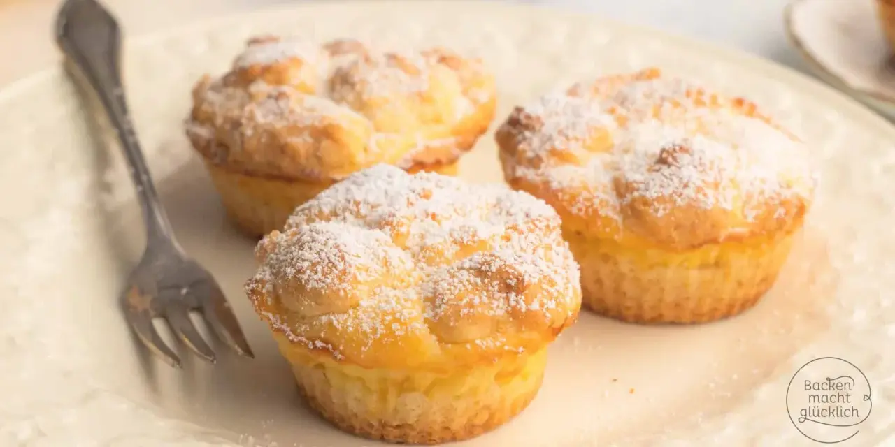 Drei luftige cheesecake muffins, bestäubt mit Puderzucker, warten auf einer Platte auf eine Gabel.