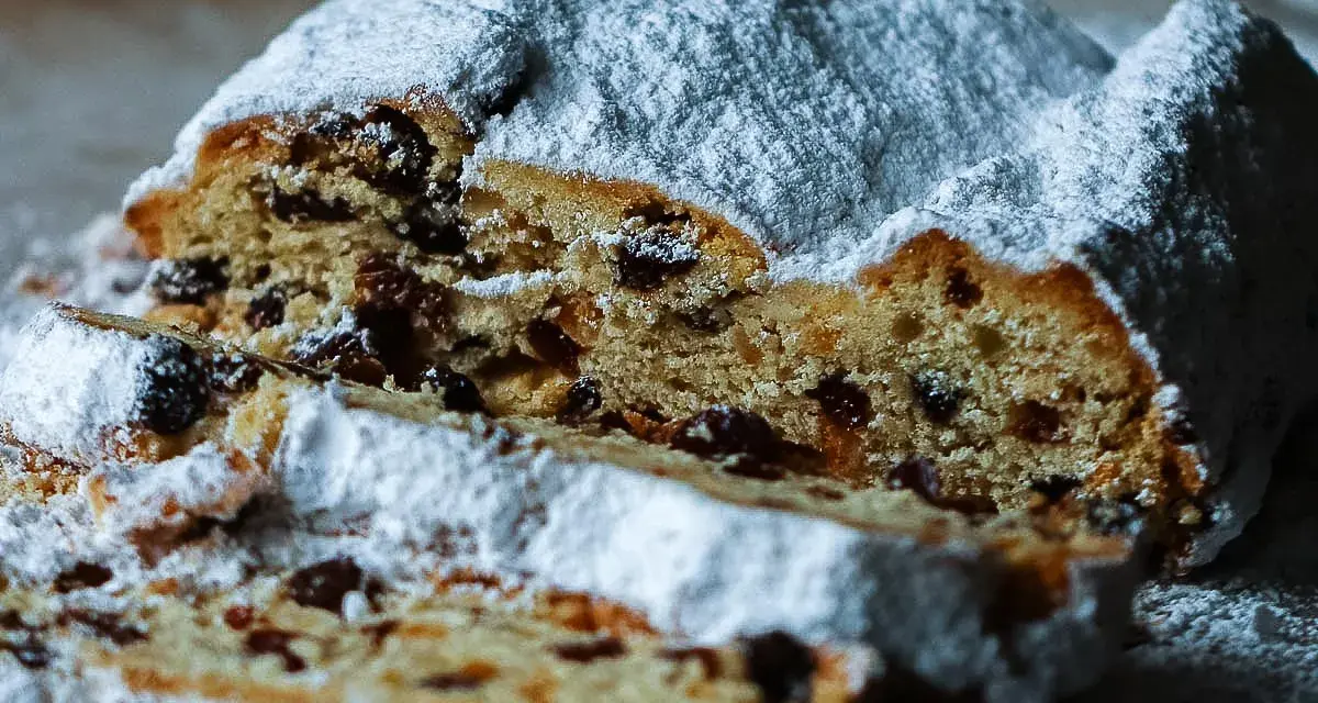 Ein saftiger Stollen, bestäubt mit Puderzucker, zeigt sein Inneres voller Rosinen. Ein köstliches Stollen Rezept zum Nachbacken.