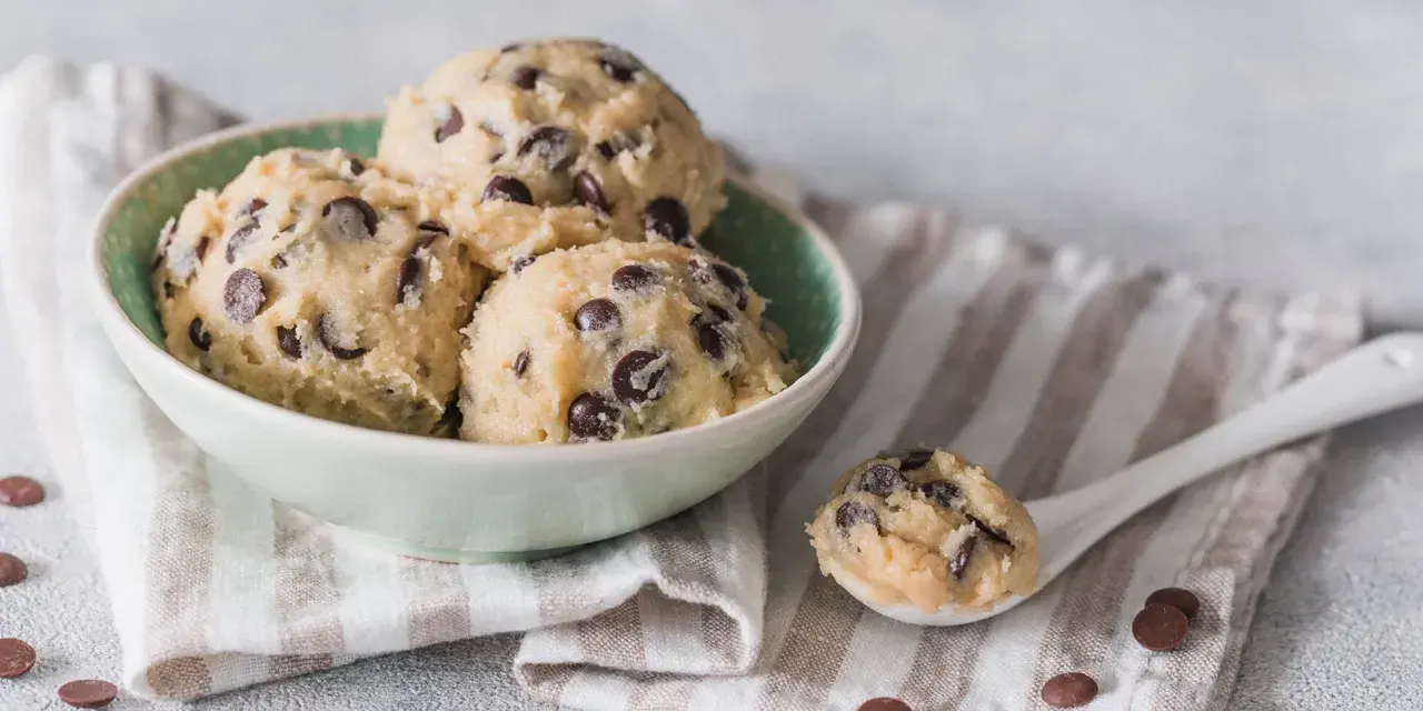 Schüssel mit Kugeln von Cookie Dough Rezept, Löffel mit Teig und Schokostückchen.