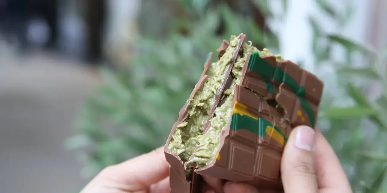 Schokoladenriegel mit grüner Füllung, inspiriert vom Dubai Schokolade Rezept, wird von Händen gehalten.