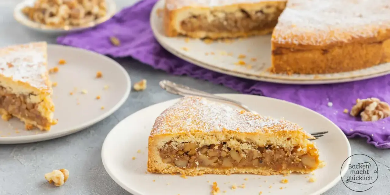 Ein Stück Nusstorte mit Puderzucker bestreut, perfekt für ein leckeres nusstorte rezept. Walnüsse liegen daneben.
