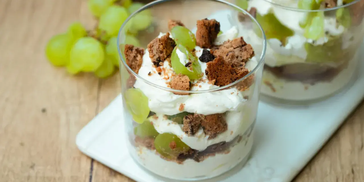 Cremiges Dessert im Glas mit grünen Trauben und zerbröselten Keksen. Ein süßer Genuss, der an einen Trauben-Keks-Traum erinnert.