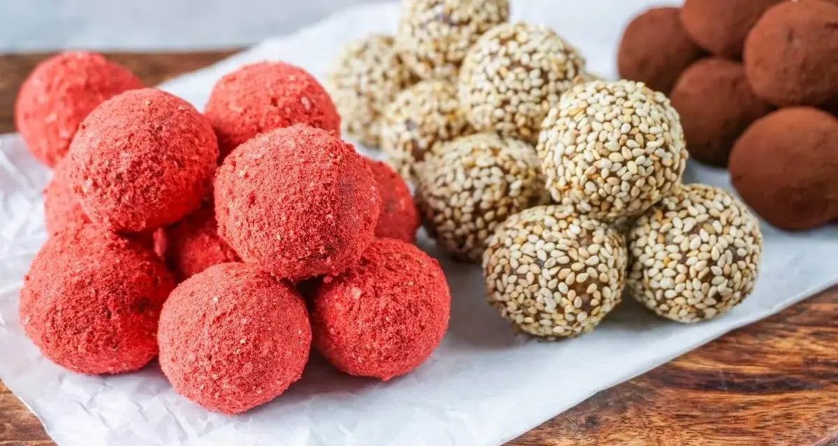 Drei Sorten leckere Energy Balls: rote Erdbeer-Bällchen, mit Sesam umhüllte Kugeln und schokoladige Trüffel.