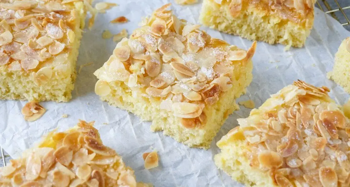 Saftiger Buttermilchkuchen mit Mandeln, bestreut mit Zucker, auf Backpapier und einem Gitter.