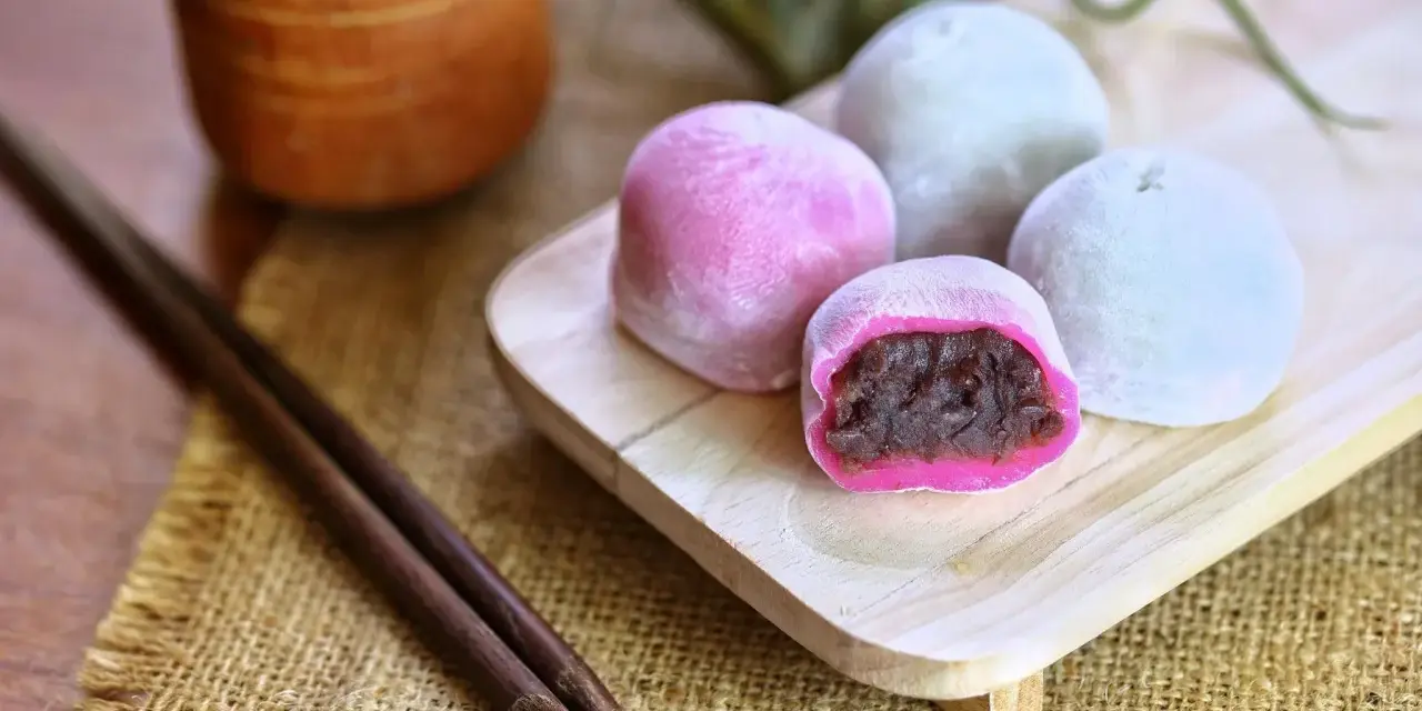 Bunte Mochi-Kugeln mit roter Bohnenpaste, bereit zum Genießen. Perfekt, um Mochi selber machen zu lernen und diese Leckereien zu kreieren.