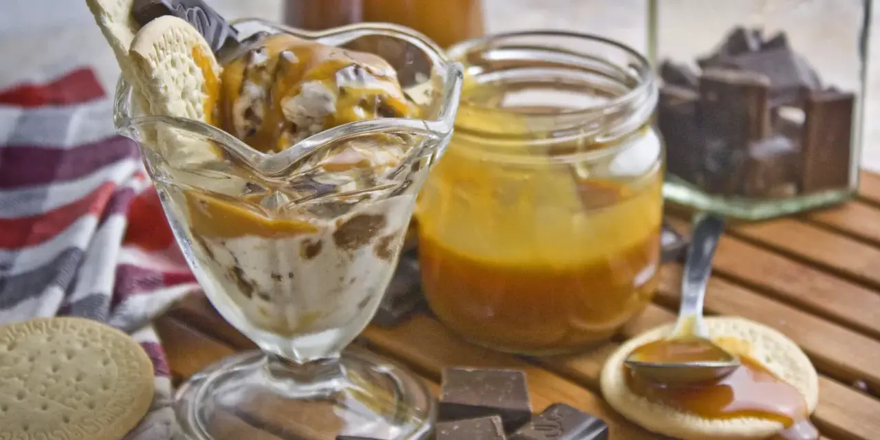 Eisbecher mit Karamellsauce, Keksen und Schokostückchen. Selbstgemachtes Karamell zum Verfeinern.