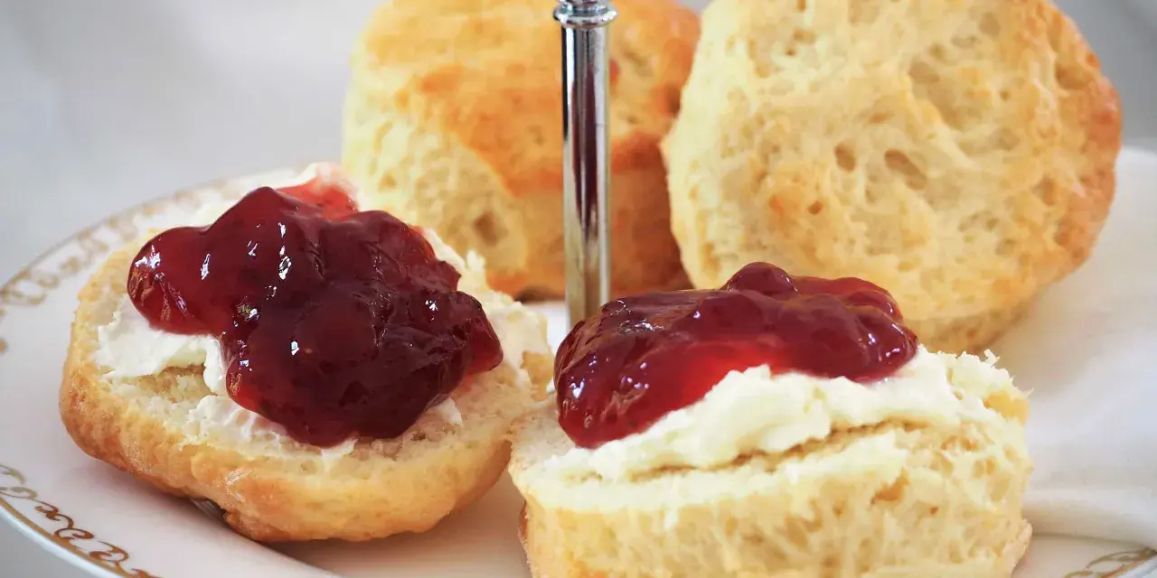 Zwei Scones mit Clotted Cream und Marmelade auf einer Etagere. Ein köstliches Rezept für Scones, perfekt für den Nachmittagstee.