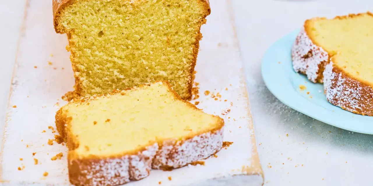 Ein saftiger Sandkuchen, bestäubt mit Puderzucker, wartet darauf, nach diesem einfachen Sandkuchen Rezept gebacken zu werden.