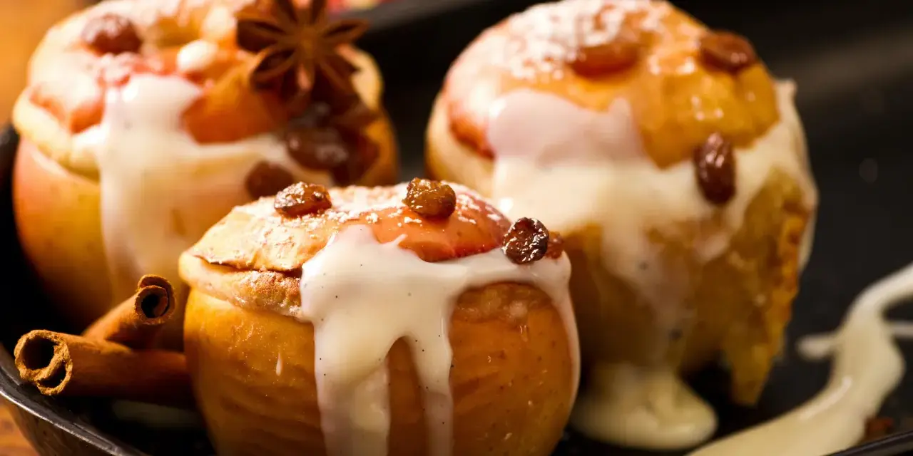 Drei köstliche Bratäpfel, übergossen mit Vanillesauce und garniert mit Rosinen und Zimtstangen. Ein perfektes Bratapfel Rezept für kalte Tage.