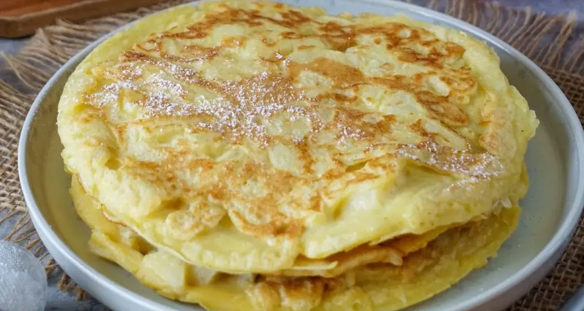 Ein Stapel goldbrauner Apfelpfannkuchen, bestäubt mit Puderzucker. Ein köstliches Apfelpfannkuchen Rezept für jeden Anlass.