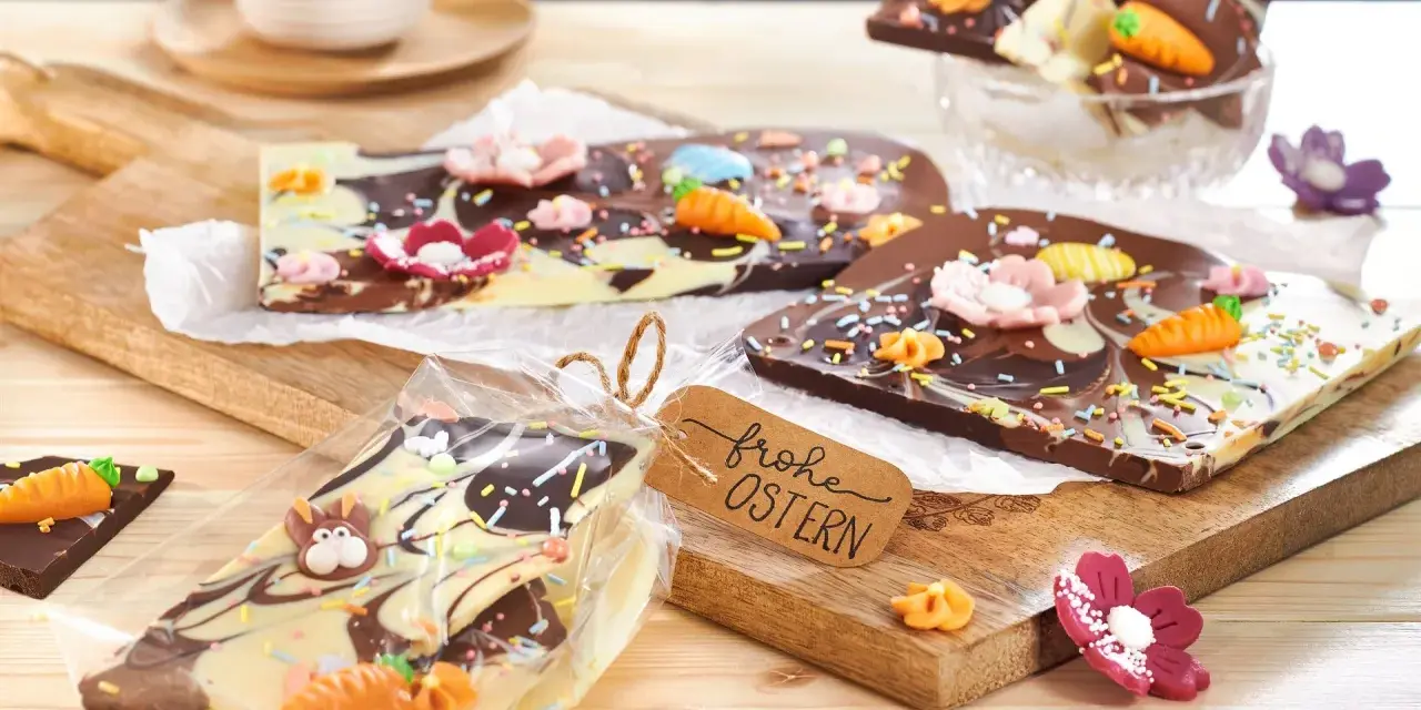 Bruchschokolade selber machen: Bunte Oster-Schokoladentafeln mit Karotten, Blumen und Streuseln, verpackt und mit "Frohe Ostern"-Anhänger.