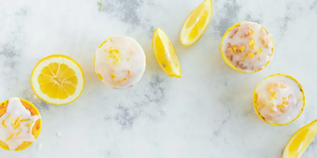 Erfrischende Zitronenmuffins mit Zuckerguss und Zitronenspalten. Ein tolles Rezept für zitronenmuffins!