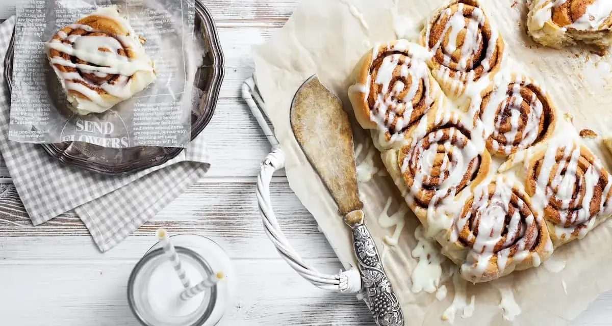 Frisch gebackene schwedische Zimtschnecken mit Zuckerguss, serviert mit einem Glas Milch.