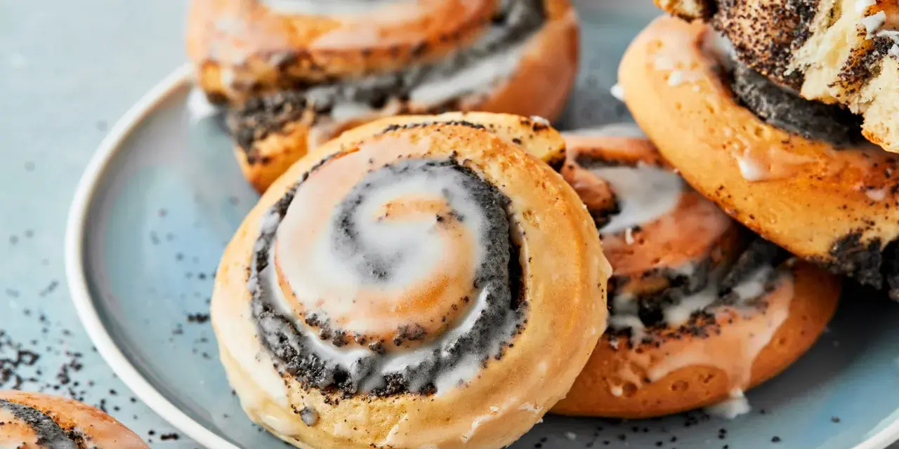 Saftige Mohnschnecken mit Zuckerguss auf einem blauen Teller. Dieses Bild inspiriert zum Nachbacken mit einem einfachen Mohnschnecken Rezept.