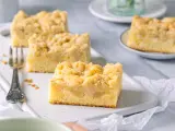 Saftiger Apfelkuchen mit Streuseln, perfekt für eine Kaffeepause. Ein Stück ist schon auf einer kleinen Platte angerichtet.