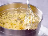 Ein Schneebesen mit cremigem Teig, bereit für ein Buttercreme Rezept.