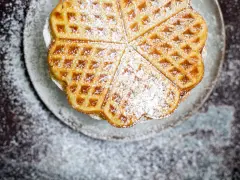 Herzförmige Bananenwaffeln, bestäubt mit Puderzucker, auf einem Teller. Ein süßer Genuss für jeden Tag.