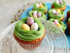 Oster-Cupcakes mit grünem Frosting als Nest und bunten Schokoladen-Eiern.