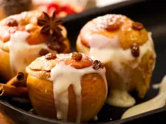 Drei köstliche Bratäpfel, übergossen mit Vanillesauce und garniert mit Rosinen und Zimtstangen. Ein perfektes Bratapfel Rezept für kalte Tage.