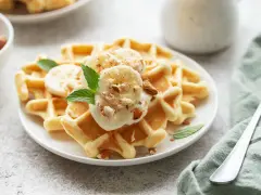 Goldbraune Skyr Waffeln mit Bananenscheiben, gehackten Mandeln und Minze. Ein köstlicher Start in den Tag!