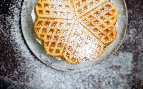 Herzförmige Bananenwaffeln, bestäubt mit Puderzucker, auf einem Teller. Ein süßer Genuss für jeden Tag.