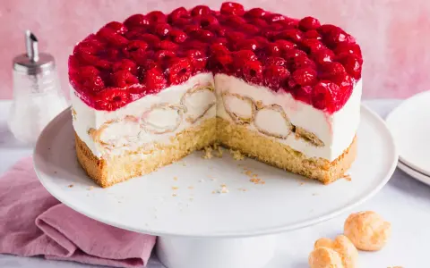 Eine köstliche Windbeutel Torte mit frischen Himbeeren und Sahne. Kleine Windbeutel sind in die cremige Füllung eingebettet.