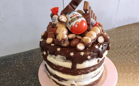 Schokoladentorte mit Kinder-Überraschungsei, Schoko-Bons und vielen weiteren Süßigkeiten dekoriert.