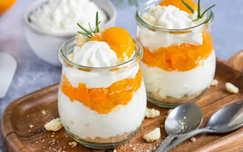 Zwei Gläser mit einem schnellen Dessert aus Mandarinen und Sahne, garniert mit Rosmarin.