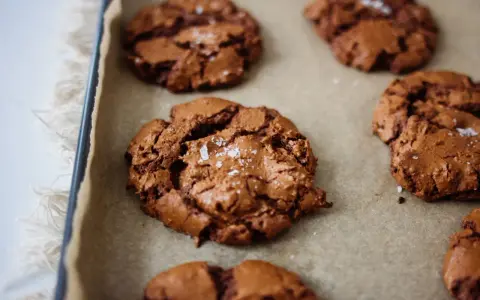 Saftige schoko cookies mit Meersalzflocken auf Backpapier, bereit zum Genießen.