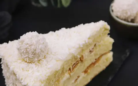 Ein Stück Raffaello Torte, bedeckt mit Kokosraspeln und einer Raffaello-Kugel.