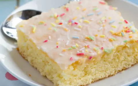 Ein Stück saftiger Fantakuchen mit Zuckerguss und bunten Streuseln, perfekt für das Fantakuchen Rezept.