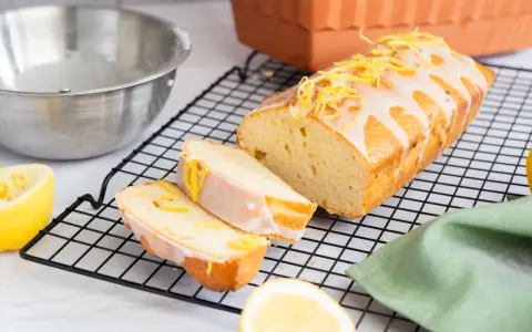 Ein saftiger Zitronenkuchen, frisch aus dem Ofen, mit Zuckerguss und Zitronenschale verziert. Perfekt für ein Zitronenkuchen Rezept.