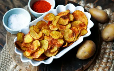 Selbstgemachte Kartoffelchips, goldbraun und knusprig, mit Salz und Paprikapulver gewürzt. So einfach ist kartoffelchips selber machen!