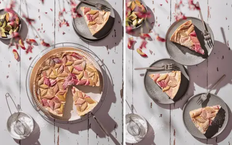 Ein köstlicher Rhabarberkuchen mit Pudding, kunstvoll arrangiert mit frischen Rhabarberstücken und Puderzucker bestäubt.