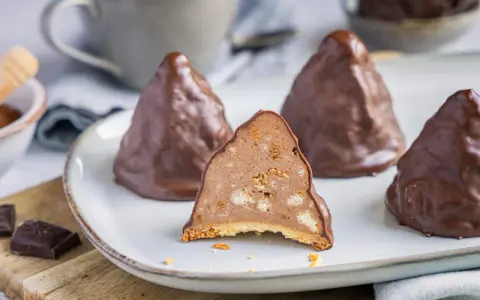 Schokoladen-Desserts, die an Granatsplitter erinnern, mit einem Stück, das die cremige Füllung mit Keksstücken zeigt. Ein köstliches granatsplitter rezept.