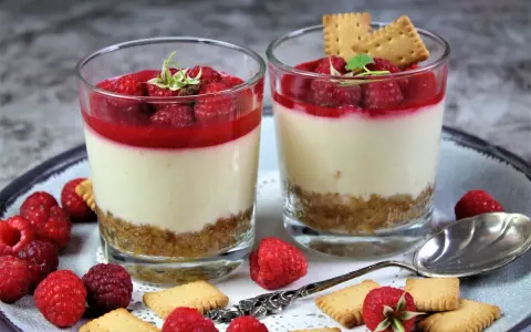 Zwei leckere Desserts im Glas mit Himbeeren und Keksen, ein süßer Genuss.