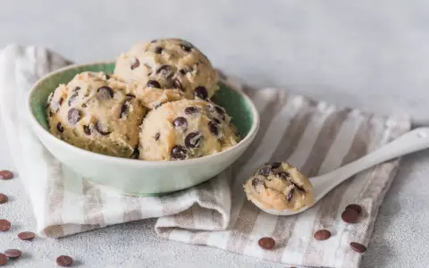 Schüssel mit Kugeln von Cookie Dough Rezept, Löffel mit Teig und Schokostückchen.