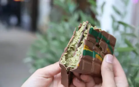 Schokoladenriegel mit grüner Füllung, inspiriert vom Dubai Schokolade Rezept, wird von Händen gehalten.