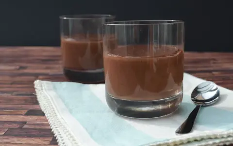 Zwei Gläser cremiger Schokopudding, perfekt zum Schokopudding selber machen. Ein Löffel liegt bereit.