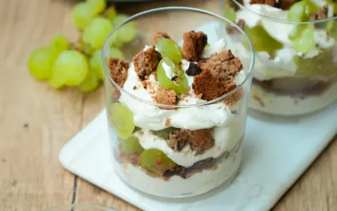 Cremiges Dessert im Glas mit grünen Trauben und zerbröselten Keksen. Ein süßer Genuss, der an einen Trauben-Keks-Traum erinnert.