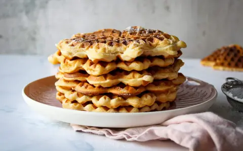 Ein Stapel goldbrauner Quarkwaffeln, bestäubt mit Puderzucker. Perfekt für ein schnelles Quarkwaffeln Rezept.