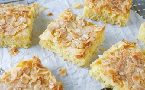 Saftiger Buttermilchkuchen mit Mandeln, bestreut mit Zucker, auf Backpapier und einem Gitter.