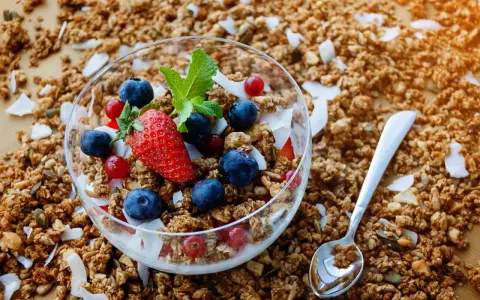Schüssel mit frischem Granola, Beeren und Kokosflocken. Perfekt für ein gesundes Frühstück, wenn du Granola selber machen möchtest.