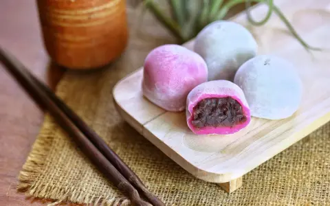 Bunte Mochi-Kugeln mit roter Bohnenpaste, bereit zum Genießen. Perfekt, um Mochi selber machen zu lernen und diese Leckereien zu kreieren.