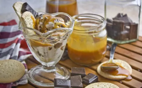 Eisbecher mit Karamellsauce, Keksen und Schokostückchen. Selbstgemachtes Karamell zum Verfeinern.
