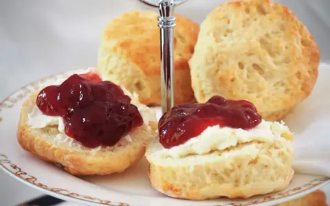 Zwei Scones mit Clotted Cream und Marmelade auf einer Etagere. Ein köstliches Rezept für Scones, perfekt für den Nachmittagstee.