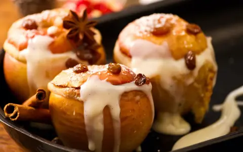 Drei köstliche Bratäpfel, übergossen mit Vanillesauce und garniert mit Rosinen und Zimtstangen. Ein perfektes Bratapfel Rezept für kalte Tage.