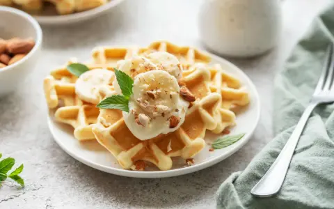Goldbraune Skyr Waffeln mit Bananenscheiben, gehackten Mandeln und Minze. Ein köstlicher Start in den Tag!