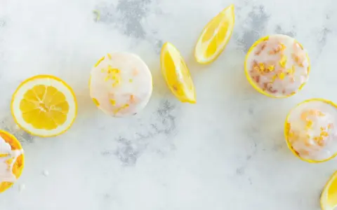 Erfrischende Zitronenmuffins mit Zuckerguss und Zitronenspalten. Ein tolles Rezept für zitronenmuffins!