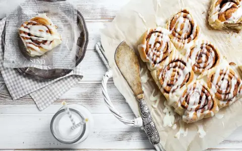 Frisch gebackene schwedische Zimtschnecken mit Zuckerguss, serviert mit einem Glas Milch.